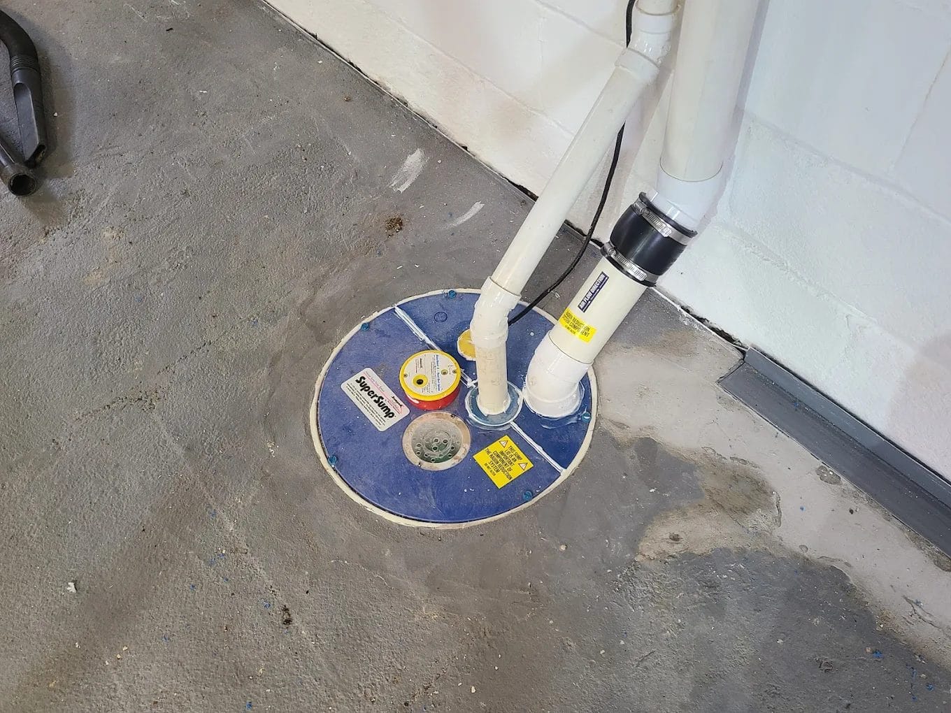 White piping for radon mitigation that's going through the floor of a basement.