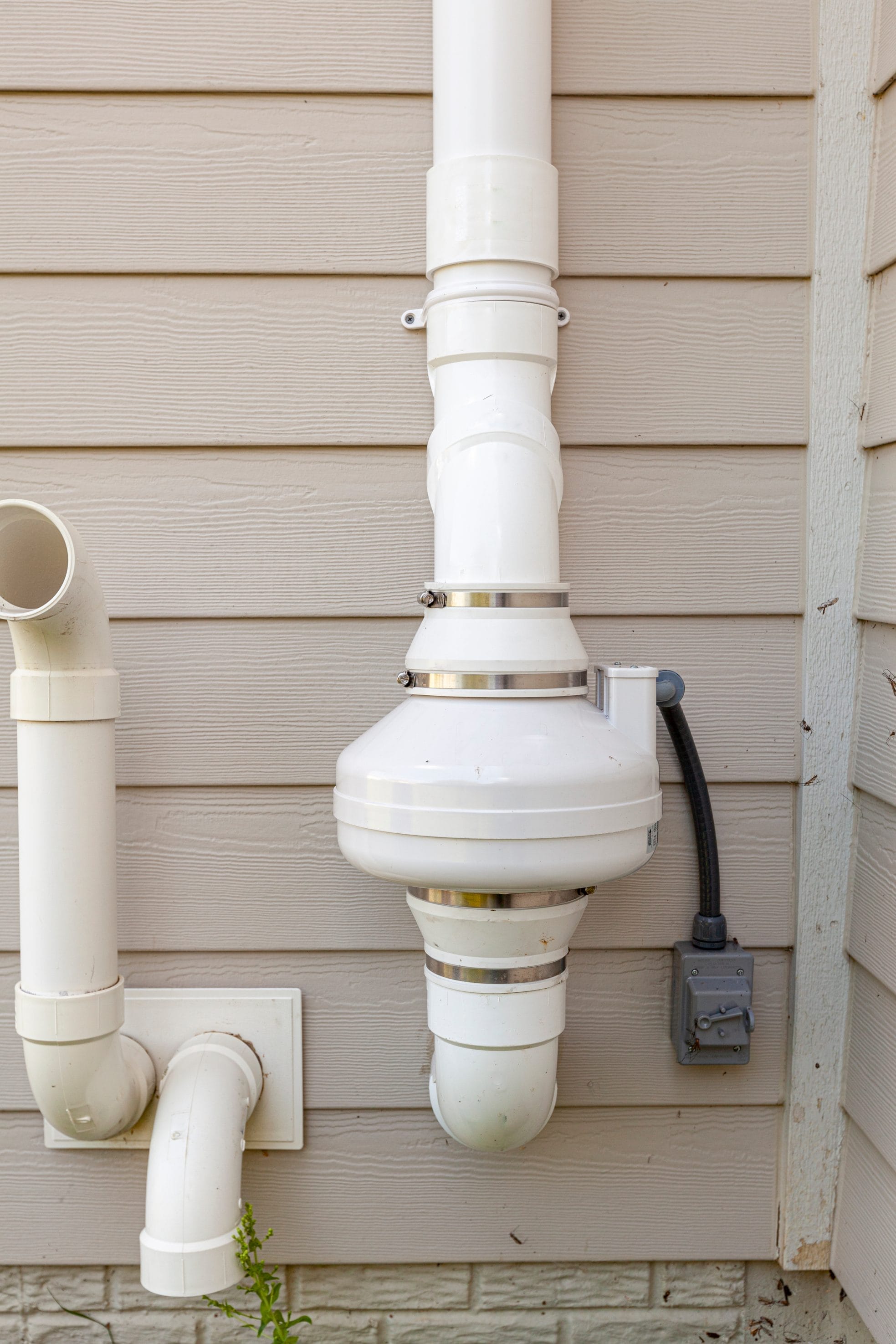 White radon mitigation equipment that is attached to the side of a home.