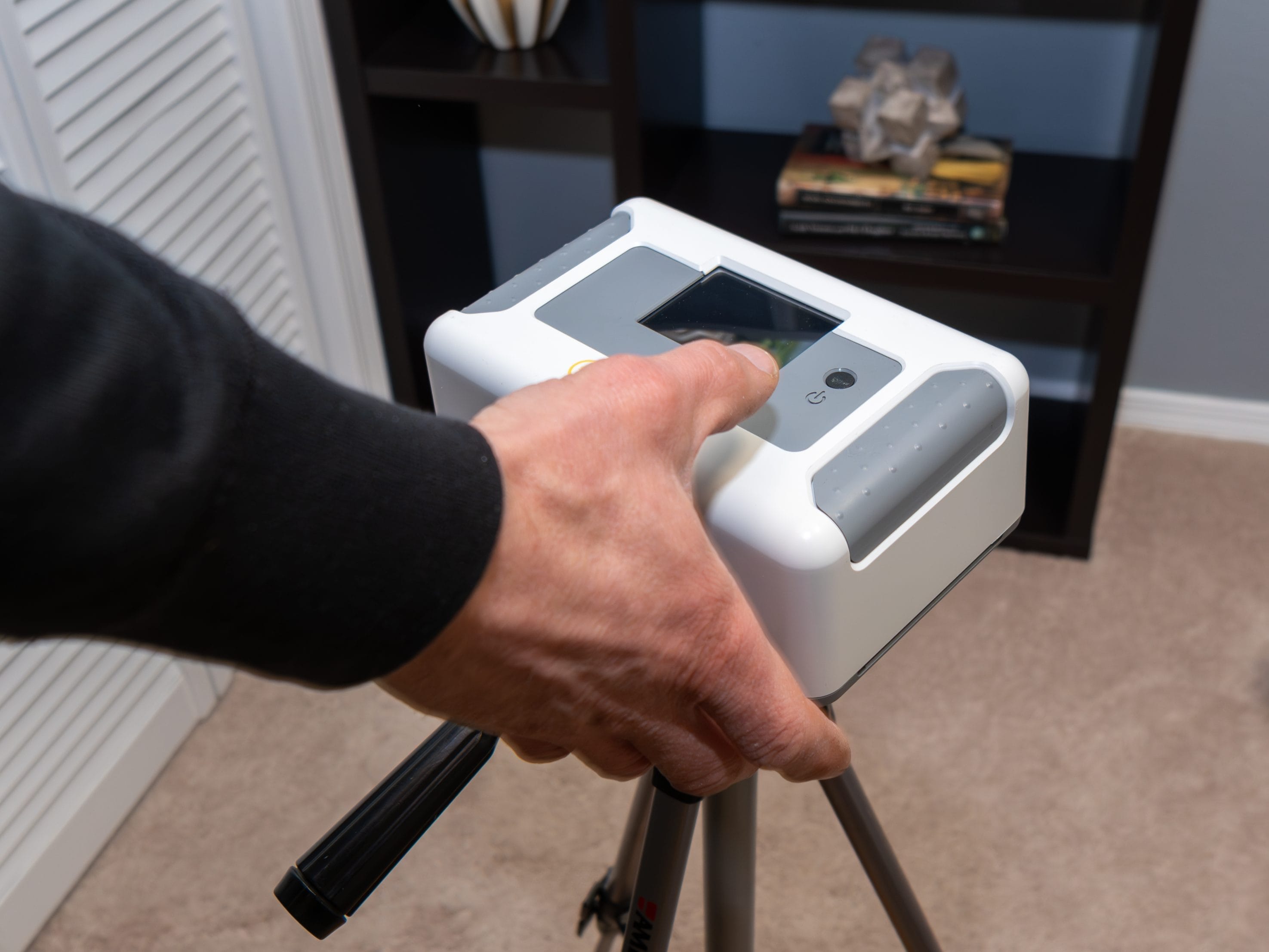 A white square radon testing device on a tripod.