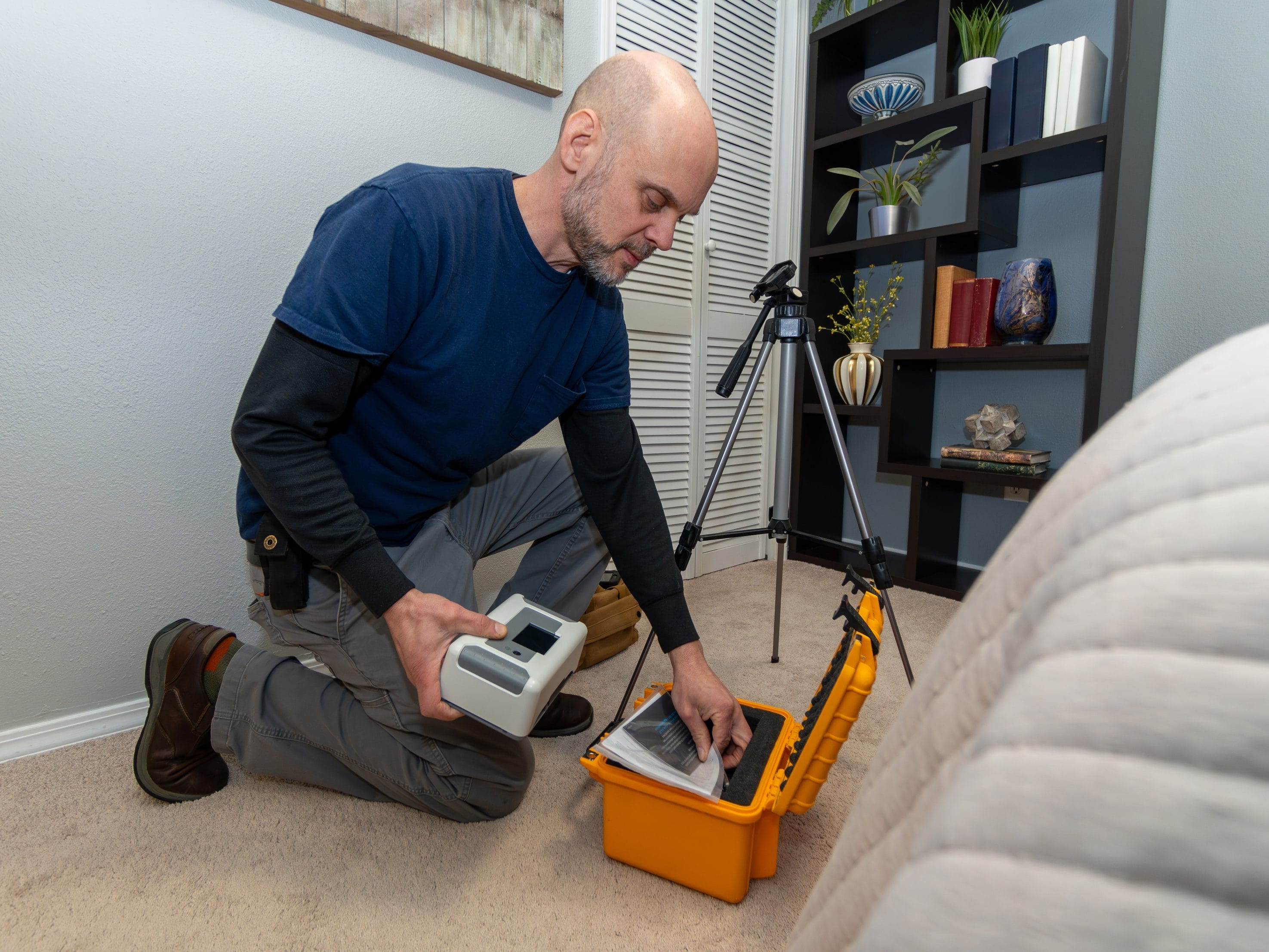 A man in a blue shirt setting up a radon testing device.